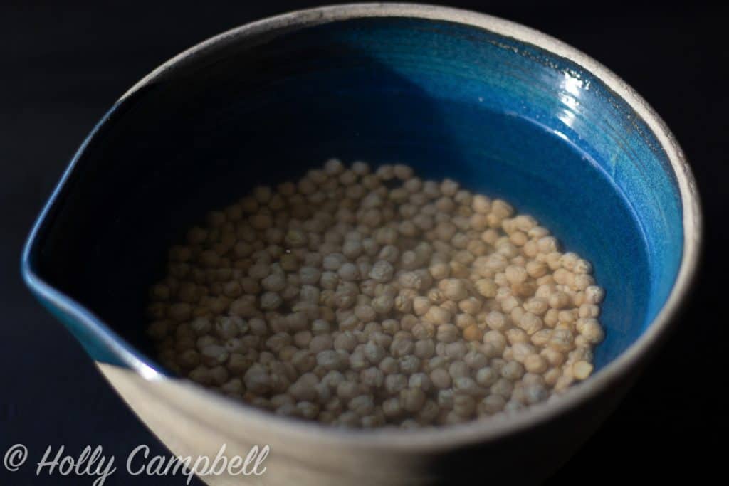 chickpeas soaking in a ceramic bowl, there is plenty of water and plenty of room for expansion