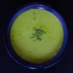 Bright green Pea Shoot Soup With Cream in a dark blue ceramic bowl